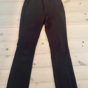 Svarta kostymbyxor från Bik Bok - Svarta kostymbyxor från Bik Bok i klassisk rak modell med bälteshällor och fickor fram. Snygg låg midja och stilrena detaljer. Passar till det mesta!