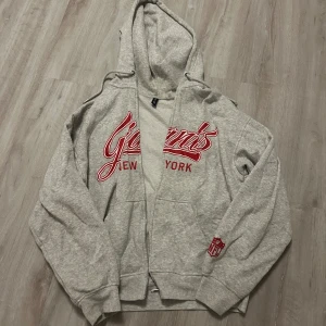 Grå Giants hoodie från H&M Divided - Säljer en grå zip-hoodie från H&M Divided med New York Giants-tryck i rött och vitt på framsidan. Pris kan diskuteras 