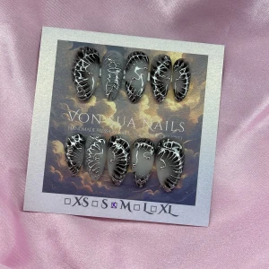Z1NK (M);Medium Almond - Handgjorda press-on naglar i svart och vitt med coola handmålade 3D silvriga mönster och små rhinestones. Naglarna har en mandelformad design och kommer i M: 16 mm, 12 mm, 12,5 mm, 11,5 mm, 10 mm. Perfekt för dig som vill ha ett edgy och unikt nagelset.