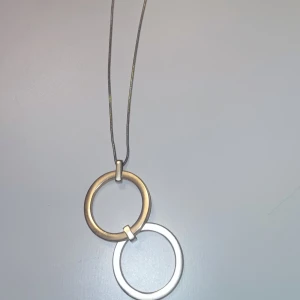 Halsband med två cirklar i guld och silver - Snyggt halsband med minimalistisk design, två stora cirklar i guld och silver hänger i en tunn kedja. Perfekt för dig som gillar stilrena och moderna smycken med en cool touch. Passar till många olika outfits och ger en trendig vibe.