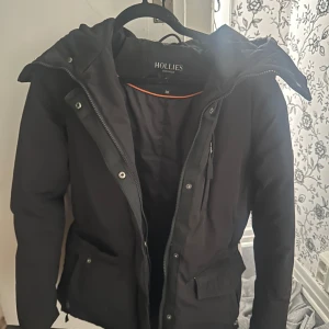 Svart parkajacka Hollies Stockholm - Svart parkajacka från Hollies  i storlek 38.  Väldigt bra skick det ändar att jag har lagat ett hål på armen se sista bilden😊