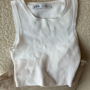 Vit ribbad linnetopp från Zara - Fräsch vit linnetopp från Zara i storlek S. Modellen är ärmlös med rund hals som ger en snygg och enkel look. Perfekt att styla med jeans eller kjol för en clean vibe.