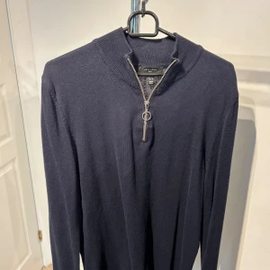 Mörkblå stickad tröja med half zip - Snygg mörkblå stickad tröja från New Look med halv dragkedja och ribbad krage. Perfekt för dig som gillar stilrena plagg med en modern touch. Tröjan har långa ärmar och är tillverkad i mjukt material som känns skönt mot huden.