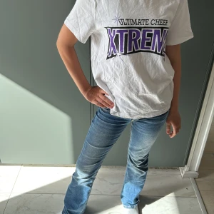 Ultimate Cheer Xtreme t-shirt vit S - Vit t-shirt från Ultimate Cheer Xtreme i storlek S med tryck i lila och svart både fram och bak. Modellen är klassisk med rund hals och korta ärmar. Materialet är mjuk bomull, perfekt för dig som gillar cheerleading och vill ha en chill stil.priset diskuteras