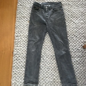 Levi's 501 grå jeans W25 L30 - Snygga grå Levi's 501 jeans med klassisk femficksdesign och raka ben. Jeansen har hög midja och är tillverkade i slitstarkt bomullsmaterial. Perfekt för dig som gillar en tidlös och chill stil. Passar dig som vill ha ett par jeans med cool vintage vibe.