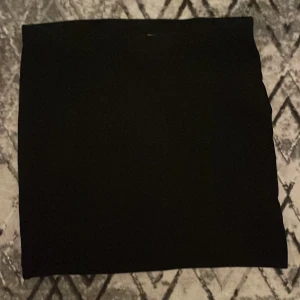 Svart kortkjol i enkel design - Säljer en svart kortkjol med rak och stilren form. Kjolen är helt enfärgad och har en klassisk look som funkar till många olika stilar. 