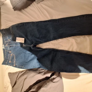 Blå jeansbyxor i klassisk modell M - Snygga blå jeansbyxor från Snake i klassisk rak modell med fem fickor och kontrastsömmar. Jeansen har normal passform och är tillverkade i slitstarkt denimtyg. Perfekta för dig som gillar enkel och tidlös stil. Oanvända och nytt skick!