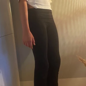 Svarta yogapants - Säljer ett par svarta yogapants med bootcut-snitt och låg midja. De är stretchiga och sitter tight över låren men blir vidare nedtill. Perfekta om du gillar en clean och enkel look med lite 90-talsvibe. Passar dig som vill ha bekväma och snygga byxor till vardags.