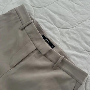 Beige wide kostymbyxor från Bik Bok - Snygga beige kostymbyxor från Bik Bok i storlek 38.  Har använt 1 gång. Super sköna kostymbyxor som är stretchiga och mid Waist