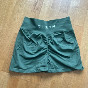 GTECH seamless contour  - Snygga gröna träningsshorts från GTECH med hög midja och ribbad linning. Materialet är stretchigt och består av 90% nylon och 10% spandex, vilket gör dem riktigt sköna och följsamma. Baktill finns en snygg rynkdetalj som framhäver formen. Perfekta för gymmet eller löprundan. I bra skick finns dock en liten reva i sömnen vilket syns på bilderna⭐️
