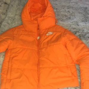 Orange pufferjacka från Nike - Storlek: 38-40 Orginal pris: 600kr och andvänd endast 2 gånger, Jag säljer den för att färgen passar inte mig. Väldigt varm, går och andvända kalla vinterdagar även kalla höstdagar