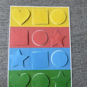 Färgglad formpusselbräda för barn - Säljer en pedagogisk formpusselbräda i kartong med former i gult, rött, blått och grönt. Innehåller hjärta, fyrkant, cirkel och stjärna. Varje form har kardborre på baksidan för enkel fastsättning. Perfekt för att lära sig färger och former.