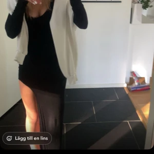 Svart långklänning med slits - Snygg svart långklänning med en djärv slits på sidan. Klänningen har långa ärmar och en tight passform som framhäver figuren. Perfekt för en kväll ute eller en speciell tillställning.