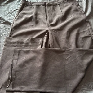 Svarta kostymbyxor med pressveck - Klassiska svarta kostymbyxor med pressveck och diskreta fickor. Byxorna har normal passform och stängs med dragkedja och knapp framtill. Perfekta för en stilren look.