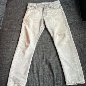 Ljusgrå jeansbyxor från Jack & Jones - Säljer ett par ljusgrå jeansbyxor från Jack & Jones, modell Chris Loose. Byxorna har fem fickor, gylf med dragkedja och knapp samt klassisk jeanslook. Passformen är loose och materialet är bomull.