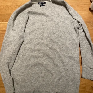 Ljusgrå tröja från Tommy Hilfiger - Säljer en stilren ljusgrå tröja från Tommy Hilfiger i en mjuk blandning av ull och kashmir. Tröjan har lång ärm och klassisk passform, perfekt för lager-på-lager under kyliga dagar. Det står 100% wool cashmere vilket jag int fattar vad de innebär