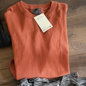 Rostfärgad stickad tröja från H&M - Säljer en ny stickad tröja från H&M. Tröjan har rund halsringning och långa ärmar, Storlek L