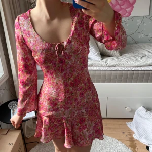 Blommig sommarklänning från Zara - Supersöt miniklänning från Zara med blommigt mönster i rosa och grönt. Klänningen har lång ärm, v-ringning med rosett och lätt volang i kjolen. Perfekt för sommaren!🌸😍Storlek M men skulle säga mer som S