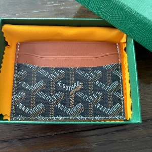 Kortfodral från GY - Säljer ett exklusivt kortfodral från GY i brunt och svart med det klassiska GY-mönstret. Fodralet har flera kortfack och är tillverkat i skinn med detaljer i syntet. Perfekt för att hålla ordning på dina kort.