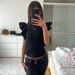 Svart zara topp med volangärmar - Säljer en svart Zara topp med stora volangärmar och rund halsringning. Toppen är ribbad och har en tight passform som framhäver figuren. Stl S men passar oxå perfekt som en Xs! OBS! Finns inte att köpa längre!