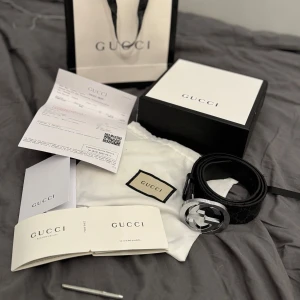 (Äkta)Svart skärp från Gucci med silverfärgat GG-spänne - Säljer ett svart bälte från Gucci med klassiskt GG-mönster och stort, silverfärgat GG-spänne. Bältet är gjort i skinn och har tydliga Gucci-detaljer. Perfekt accessoar för att lyfta din outfit. Det är lite slitet som man ser på bilderna men inget man tänker på fraktas direkt vid köp