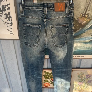 Feta jeans från Nudie - Feta nudies med asfet tvätt. De har en lätt tvättad look och är perfekta för en avslappnad stil. Priset är ej hugget i sten, hör av dig vid funderingar!