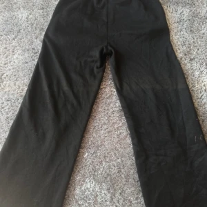 Svarta mjukisbyxor - Svarta mjukisbyxor med breda ben och elastisk midja med dragsko. Byxorna har en avslappnad passform och är perfekta för en chill stil. Mjukt material och fickor i sidorna. 