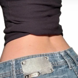 Lågmidjade bootcut jeans med metallbricka - Säljer ett par klassiska blå jeans med låg midja och bootcut passform. Jeansen har en snygg metallbricka bak på linningen och femficksdesign. Perfekta för dig som gillar en retro vibe och vill ha ett par jeans som sticker ut lite extra😁