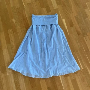 Ljusblå långkjol från Gina Tricot - Säljer en ljusblå långkjol från Gina Tricot. Kjolen har en mjuk, bred linning och är tillverkad i ett tunt, flowy material som ger ett luftigt intryck. Perfekt för varma dagar och enkel att styla med olika toppar. Den är helt oanvänd. 