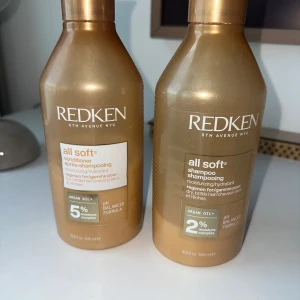 Redken All Soft schampo och balsam - Redken All Soft schampo och balsam i stora guldiga flaskor, båda med arganolja. Schampot återfuktar och mjukgör torrt hår, balsamet ger extra mjukhet. Flaskorna rymmer 500 ml vardera och har tydlig märkning med vit och guldig etikett. Mängd kvar syns på bilden
