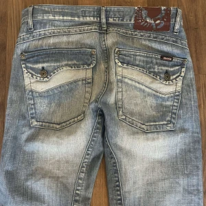 Blå jeansbyxor från Diesel - Säljer ett par blå jeansbyxor från Diesel med slitna detaljer och raka ben. Byxorna har klassiska bakfickor med knapp och en liten Diesel-logga på ena fickan. Perfekta för en avslappnad stil. Säljer åt en kompis.😊hör av er för frågor