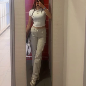 Beiga byxor från Madlady - Säljer ett par beiga byxor från Madlady med normal passform och raka ben. Byxorna har fickor framtill och stängs med dragkedja och knapp. Perfekta till många olika outfits och enkla att matcha.