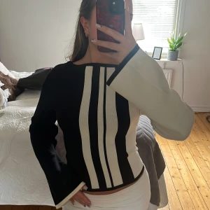 Svart och vit tröja med grafiskt mönster - Säljer en unik svart och vit tröja från Gina tricot med breda, raka ränder framtill. Tröjan har lång utsvängd ärm och fin passform, perfekt för dig som gillar en modern och stilren look. Materialet känns mjukt och stretchigt. Storlek XS