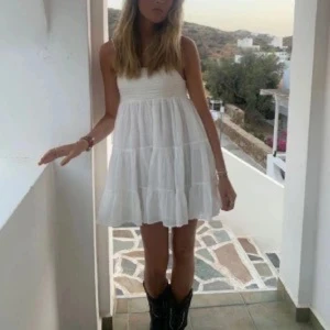 Liknande vit volang klänning zara  - Säljer en söt vit ärmlös klänning med volangdetaljer och lätt utställd kjol. Klänningen har en luftig passform och är perfekt för varma dagar. Passar dig som gillar en enkel men stilren look.