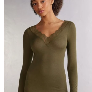 Intimissimi långärmad tröja - HELT NY, med prislapp, Har S men M e fortfarande bra. Säljer en olivgrön långärmad topp med v-ringning och fina spetsdetaljer längs halsringningen från intimissimi. Toppens material är mjukt och stretchigt, perfekt för en stilren och bekväm look.