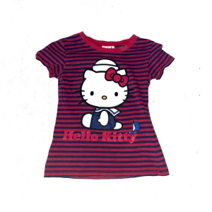 Röd och marinblå Hello Kitty t-shirt - Supergullig röd och marinblå randig t-shirt med stort Hello Kitty-tryck framtill. Den är 130 barnstorlek men funkar som en baby tee i S