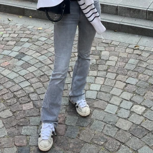 Ljusgrå lågmidjade bootcut jeans från gina - Säljer ett par ljusgrå bootcut jeans med klassisk femficksdesign. Jeansen har en normal passform och är tillverkade i denim med lätt stretch. Köpta på gina men inte kommit till så stor andvändning. 