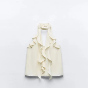 Vit ärmlös blus från Zara - Vit blus från Zara med volangdetaljer längs framsidan. Den är ärmlös och har en hög krage endast använd två gånger❣️❣️ normal i storleken❣️