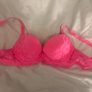 Rosa spets-bh - Säljer en snygg rosa bh med spetsdetaljer och justerbara axelband. Bh:n har vadderade kupor och vacker spets längs kanterna och bandet. Perfekt för dig som vill ha något både bekvämt och stilrent.