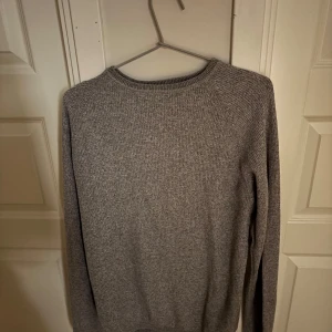 Grå stickad tröja från Selected Homme - Säljer en stilren grå stickad tröja från Selected Homme. Tröjan har rund halsringning och långa ärmar, perfekt för lager-på-lager. Enkel och klassisk design som passar till många outfits. Nice till sommarkvällar. Pris kan diskuteras.