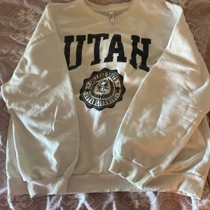 Vit sweatshirt med UTAH-tryck från ONLY - Säljer en vit sweatshirt från ONLY med svart UTAH-tryck. Har använt några gånger och har tyvärr blåa fläckar på ärmen 