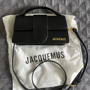 Svart handväska  - Svart handväska med guldiga detaljer och avtagbar axelrem. Logotyp: Jacquemus i guld framtill. Aldrig använd.