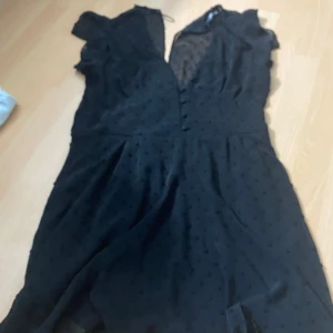 Svart prickig klänning från Zara - Säljer en svart klänning från Zara med diskreta prickar i tyget. Klänningen har korta ärmar och v-ringning, samt en lätt utställd kjol. Perfekt för dig som gillar en klassisk men trendig look.