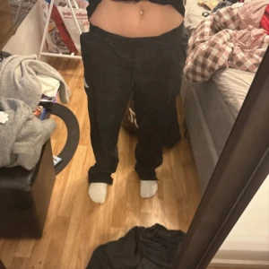 Svarta träningsbyxor från Adidas - Svarta träningsbyxor från Adidas med klassisk logga på benet. Byxorna har en avslappnad passform och resår i midjan för extra komfort. Perfekta för gymmet eller chill hemma. Säljes i storlek S.