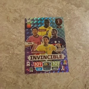 Panini FIFA World Cup Invincible kort - Säljer ett Panini FIFA World Cup Invincible samlarkort med spelarna Son, Mendy, Marquinhos och Pogba. Kortet har holografisk yta och färgglad design med landsflaggor och statistik. Perfekt för samlare av fotbollskort.