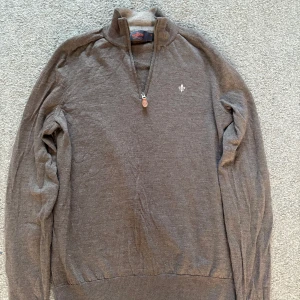 Half-zip från Morris - Säljer en brun stickad tröja från Morris med half-zip dragkedja och hög krage. Tröjan har ett litet hål på ryggen som inte syns vid använing men annars är skicket jätte bra.