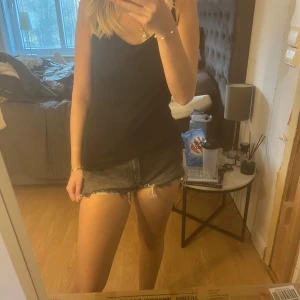 Grå jeansshorts med fransar från Zara - Säljer ett par grå jeansshorts från Zara med råa franskantade benslut. Klassisk femficksmodell och lågmidjad passform. Perfekta till sommaren och lätta att matcha med olika toppar.