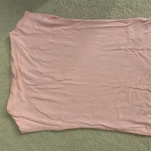 Ljusrosa kortklänning från 157 - En enkel och mjuk ljusrosa kortklänning från 157 Klänningen är ärmlös och har en rak passform, perfekt för varma dagar. Tillverkad i ett tunt och bekvämt material som känns skönt mot huden.