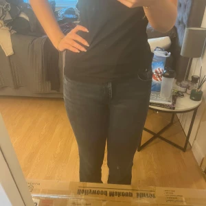 Mörkblå jeans med normal passform - Säljer ett par mörkblå jeans med klassisk femficksdesign och normal passform. Jeansen har hög midja och raka ben, samt diskreta sömmar och knappgylf. Perfekta för en stilren och enkel look.