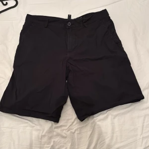 Svarta slim fit shorts från H&M - Svarta shorts från H&M i slim fit-modell. Klassisk design med knapp och dragkedja framtill, sidofickor och bakfickor med knapp. Perfekta för varma dagar och enkel att matcha med olika outfits.